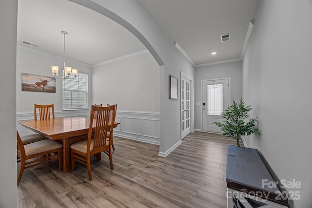 dining room featuring crown molding, an inviting chandelier, and light hardwood / wood-style floors