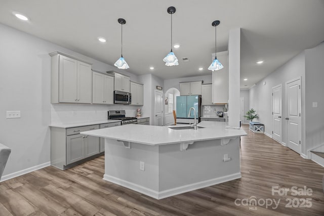 kitchen featuring decorative light fixtures, sink, gray cabinetry, a kitchen bar, and stainless steel appliances