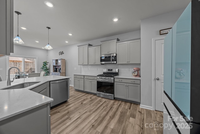 kitchen featuring appliances with stainless steel finishes, gray cabinetry, pendant lighting, and backsplash