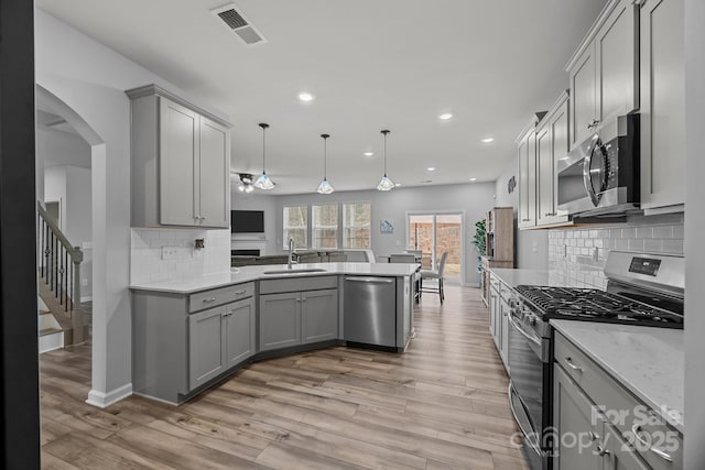 kitchen with pendant lighting, appliances with stainless steel finishes, sink, and gray cabinetry