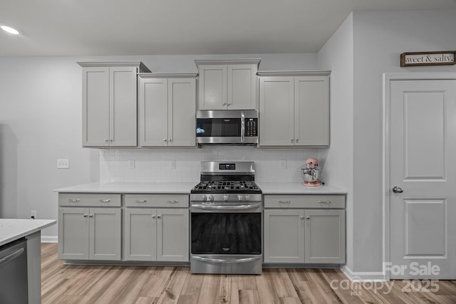 kitchen featuring stainless steel appliances, gray cabinetry, backsplash, and light hardwood / wood-style floors