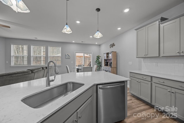 kitchen with sink, tasteful backsplash, light stone counters, dishwasher, and pendant lighting