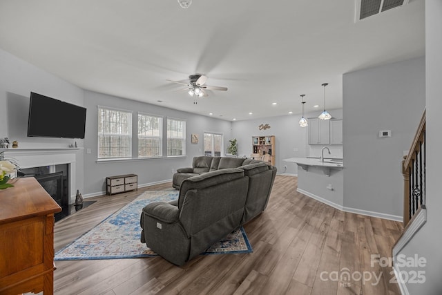 living room with sink, ceiling fan, and light wood-type flooring