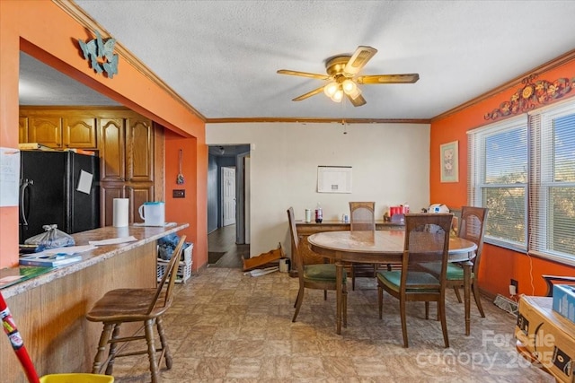 dining area with ceiling fan, crown molding, and a textured ceiling