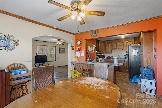 dining room with a textured ceiling, ceiling fan, and ornamental molding