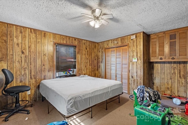 carpeted bedroom with ceiling fan, a textured ceiling, a closet, and wood walls