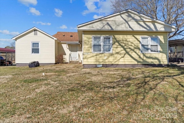 rear view of property featuring a lawn and a carport