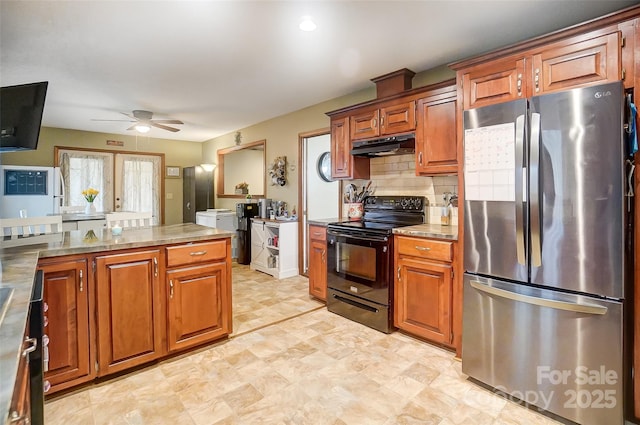 kitchen with brown cabinets, black electric range oven, backsplash, freestanding refrigerator, and under cabinet range hood