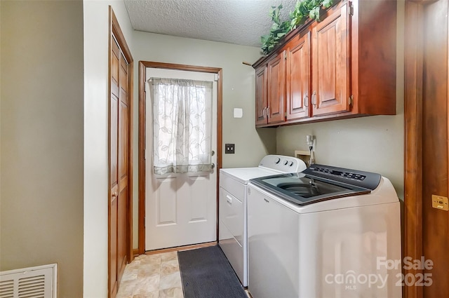 laundry area featuring cabinet space, visible vents, independent washer and dryer, and a textured ceiling