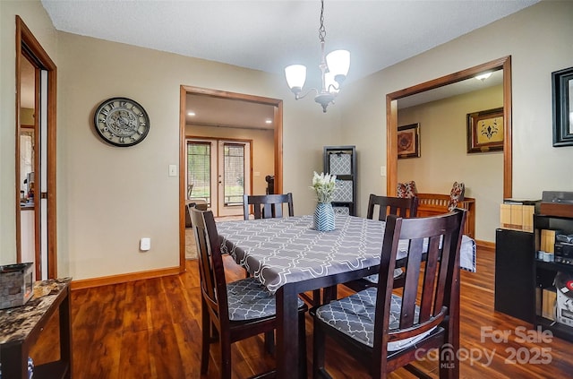 dining space with dark wood-style floors, baseboards, and a notable chandelier