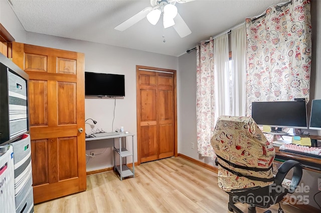 office space with a ceiling fan, light wood-style flooring, baseboards, and a textured ceiling