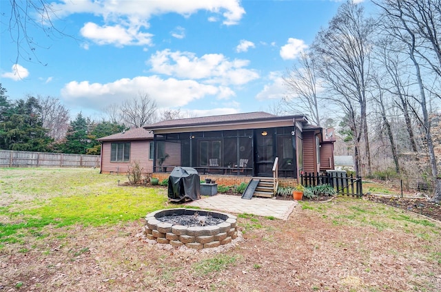 back of house with a fire pit, a lawn, fence private yard, and a sunroom