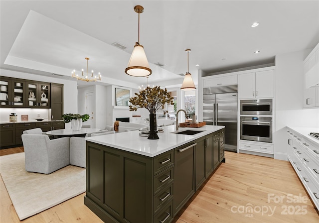 kitchen featuring appliances with stainless steel finishes, decorative light fixtures, sink, and a center island with sink