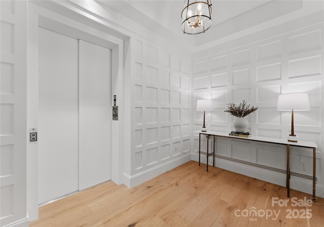 foyer with wood-type flooring, elevator, and an inviting chandelier