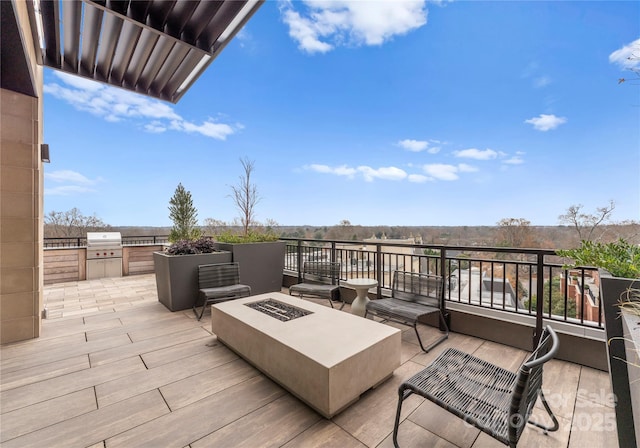 deck featuring a grill, a fire pit, a patio area, and exterior kitchen