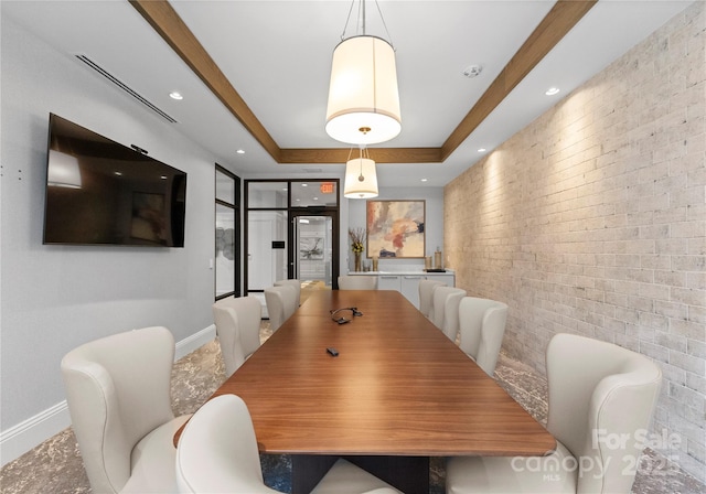 dining space with brick wall and a raised ceiling