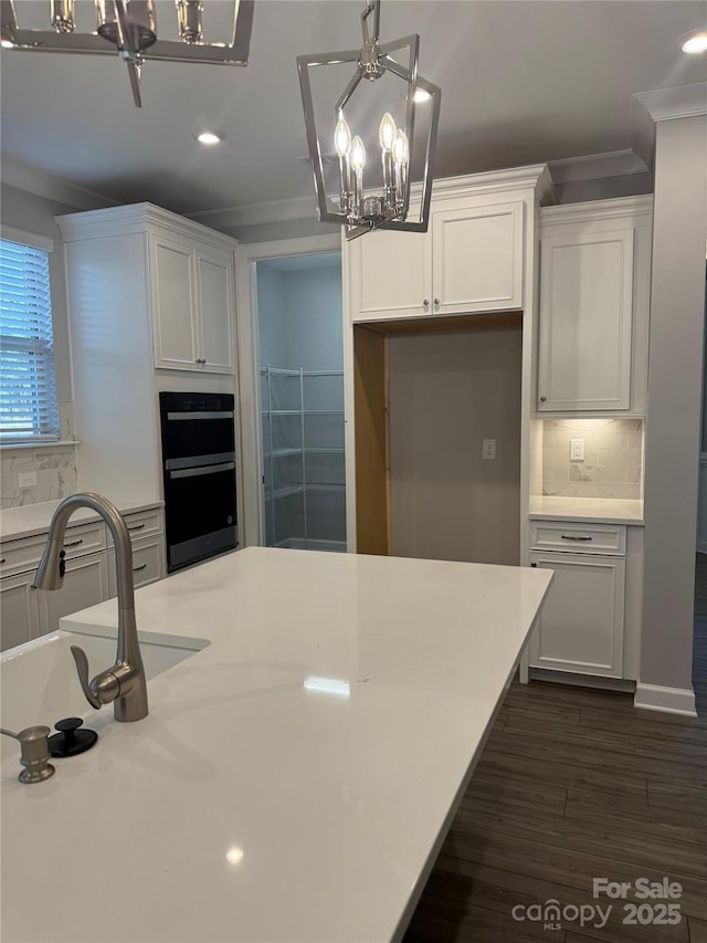 kitchen with backsplash, decorative light fixtures, a notable chandelier, double oven, and white cabinets