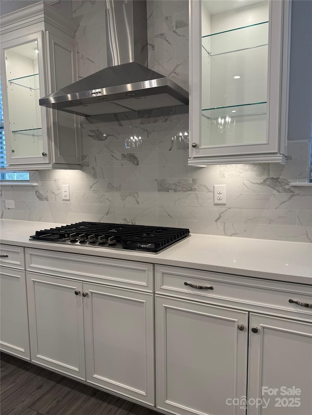 kitchen featuring stainless steel gas stovetop, white cabinetry, backsplash, dark wood-type flooring, and wall chimney exhaust hood