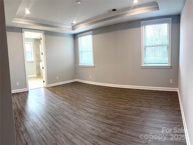 spare room featuring dark hardwood / wood-style flooring and a tray ceiling