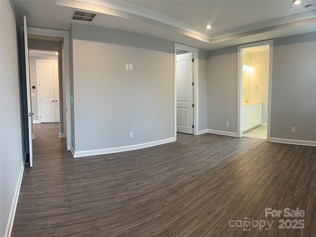 spare room featuring a raised ceiling and dark hardwood / wood-style floors