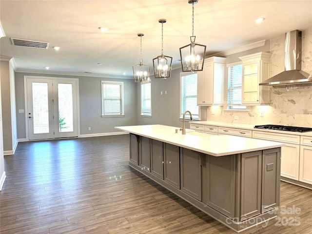 kitchen with visible vents, a large island, ornamental molding, gas cooktop, and wall chimney range hood