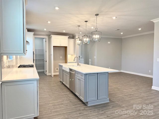 kitchen with baseboards, light countertops, wood finished floors, stainless steel appliances, and a sink