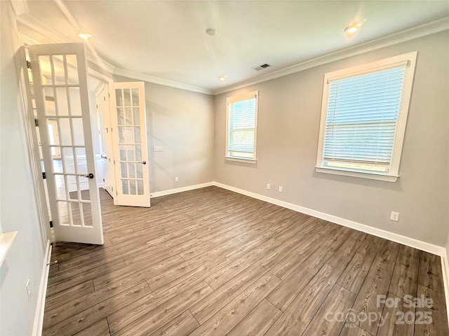 empty room with wood finished floors, visible vents, baseboards, french doors, and crown molding