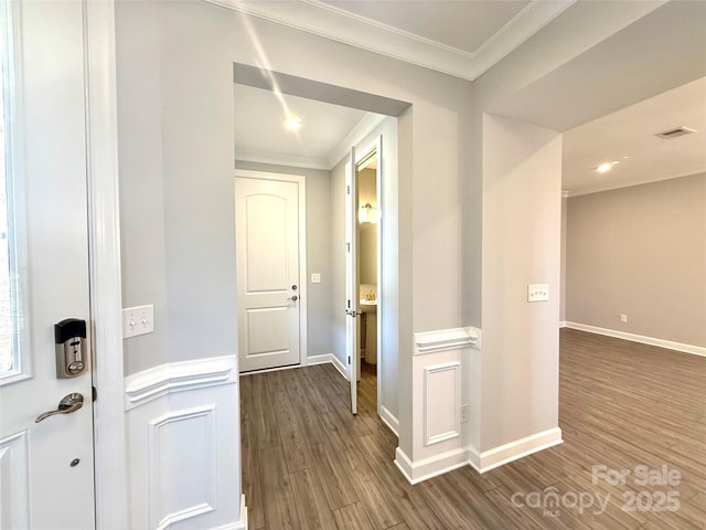 hallway featuring visible vents, baseboards, ornamental molding, and dark wood-style flooring