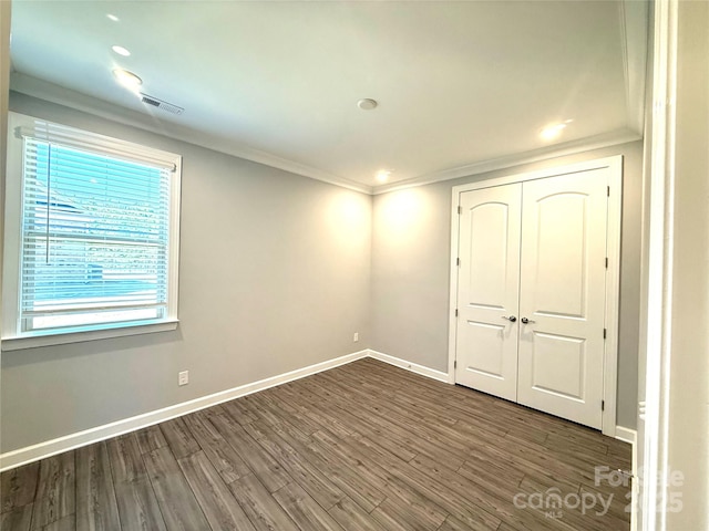 unfurnished bedroom with visible vents, crown molding, baseboards, and wood finished floors