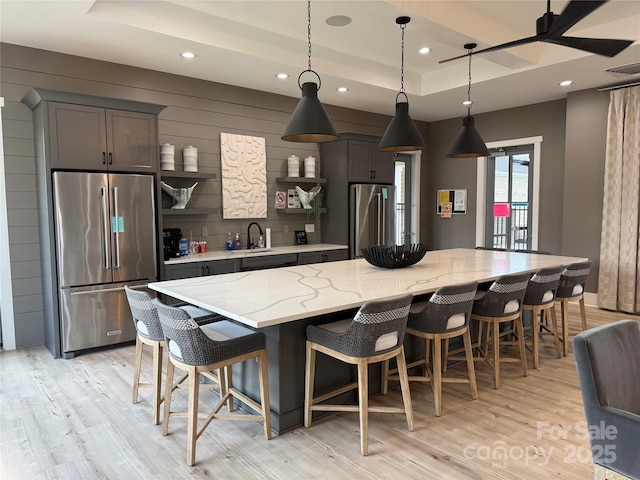 kitchen with a spacious island, high end refrigerator, a raised ceiling, and visible vents