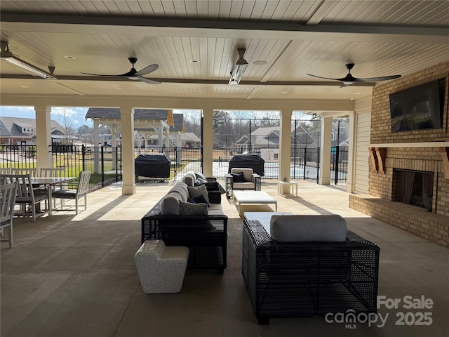 view of patio featuring an outdoor living space with a fireplace, glass enclosure, a ceiling fan, and fence