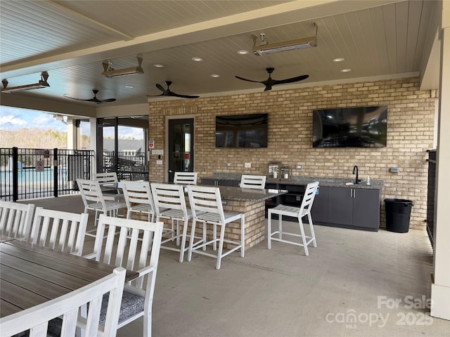 view of patio / terrace featuring a sink, outdoor dry bar, a ceiling fan, and fence