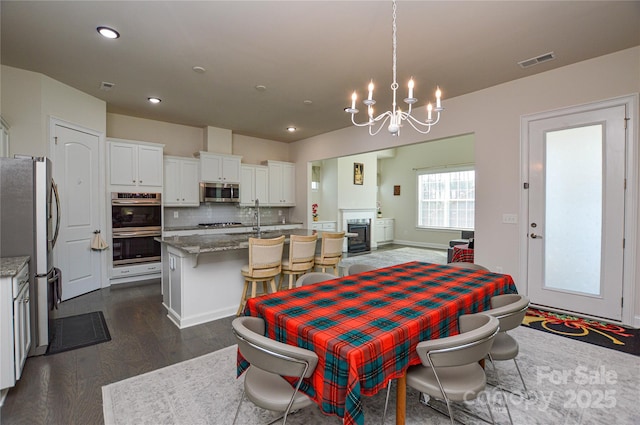 dining space featuring a chandelier, a fireplace, and dark hardwood / wood-style floors