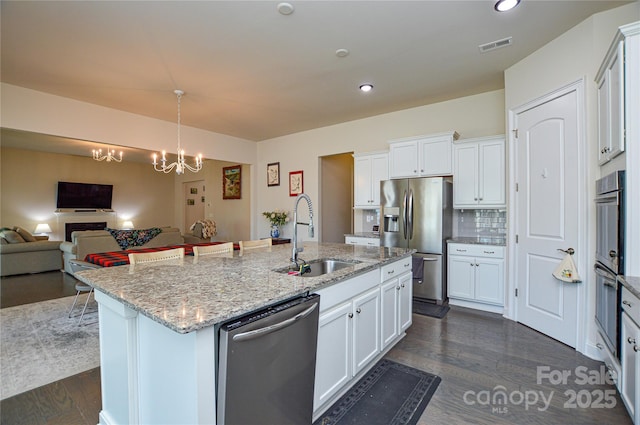 kitchen featuring sink, white cabinetry, stainless steel appliances, and an island with sink