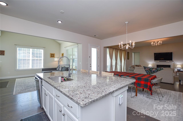 kitchen featuring decorative light fixtures, sink, white cabinetry, a kitchen island with sink, and a chandelier