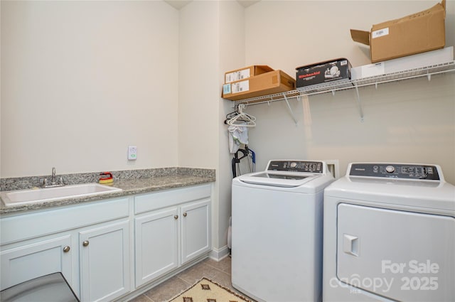 clothes washing area with cabinets, light tile patterned flooring, washing machine and clothes dryer, and sink