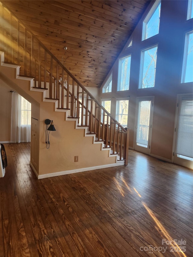 stairway featuring wood-type flooring, wooden ceiling, and high vaulted ceiling