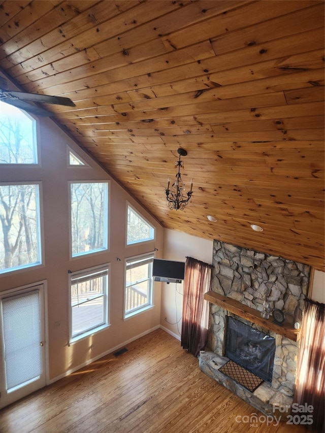 unfurnished living room featuring hardwood / wood-style flooring, a stone fireplace, high vaulted ceiling, and wood ceiling