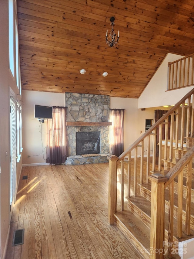 unfurnished living room featuring high vaulted ceiling, a fireplace, hardwood / wood-style flooring, wooden ceiling, and an inviting chandelier