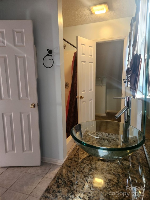 bathroom with tile patterned flooring, sink, a shower, and a textured ceiling