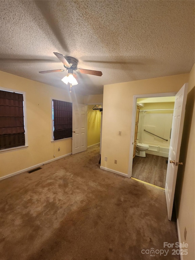 unfurnished bedroom featuring carpet floors, connected bathroom, a textured ceiling, and ceiling fan