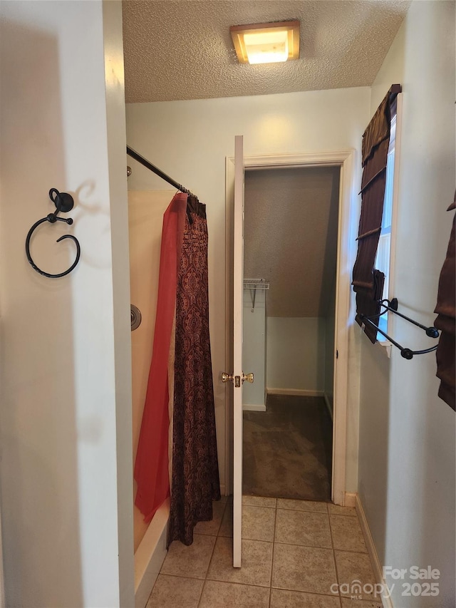 bathroom with curtained shower, tile patterned flooring, and a textured ceiling