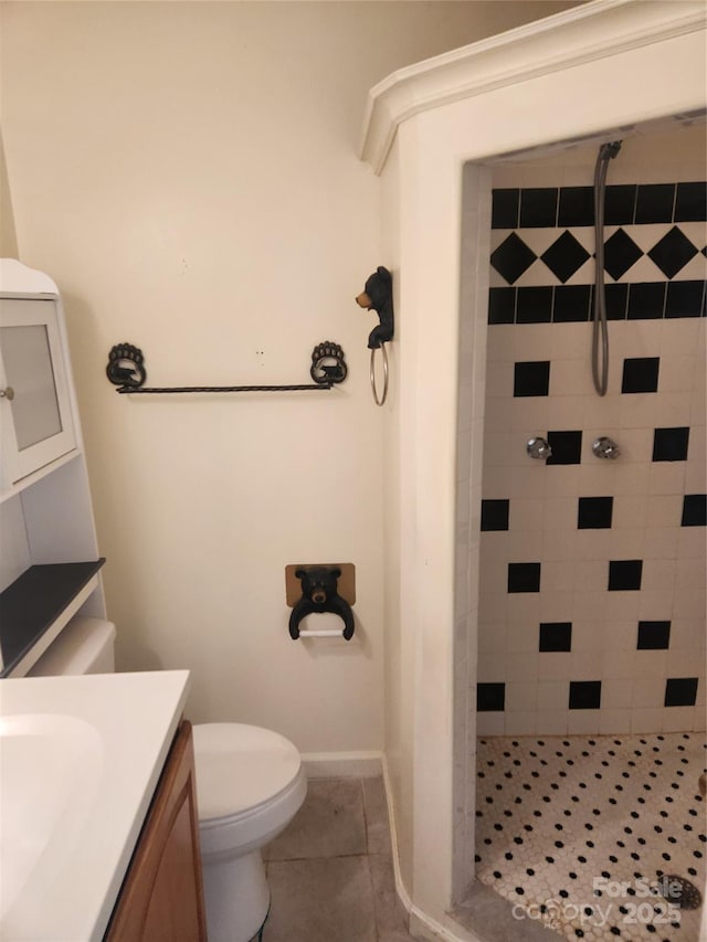 bathroom featuring tile patterned floors, vanity, toilet, and a tile shower