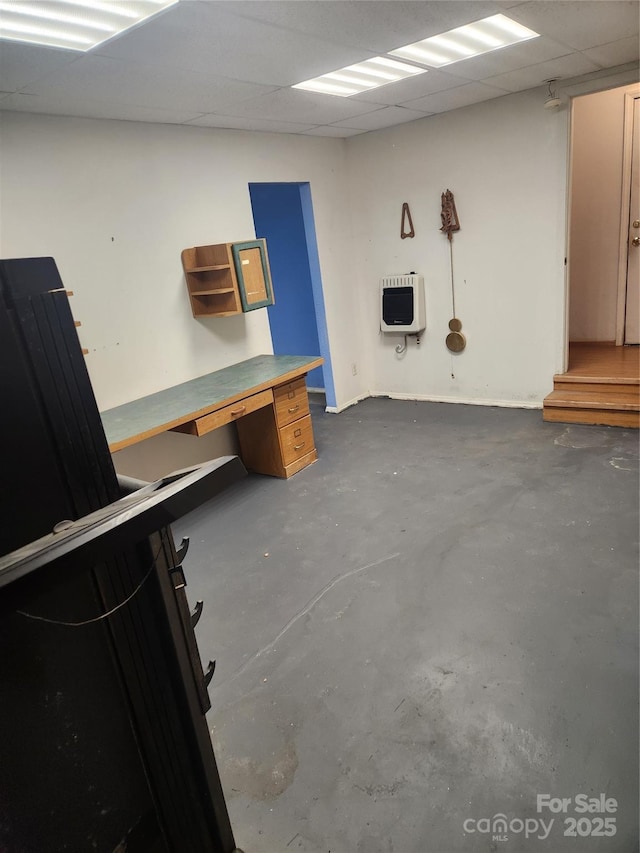 basement with a paneled ceiling and heating unit