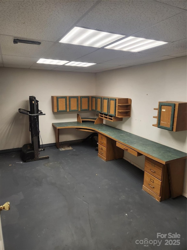 unfurnished office featuring built in desk and a paneled ceiling