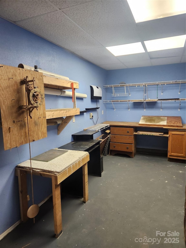 home office with a paneled ceiling and a workshop area