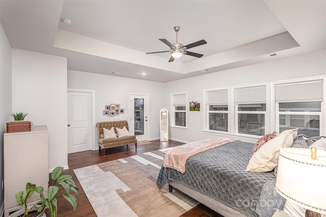 bedroom with ceiling fan, dark wood-type flooring, and a raised ceiling