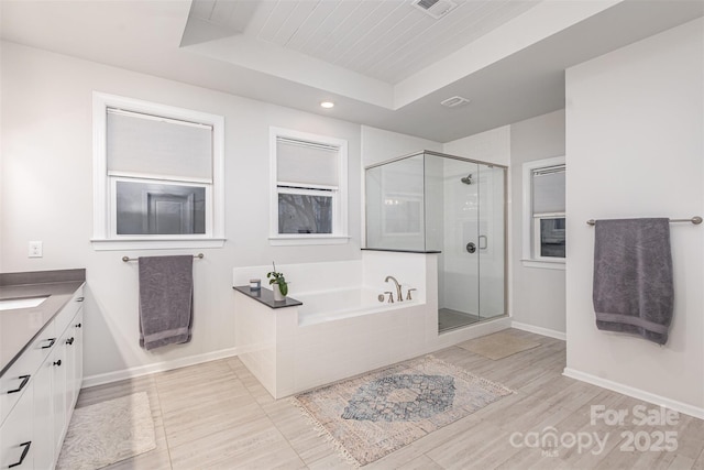 bathroom with wood-type flooring, a tray ceiling, vanity, and independent shower and bath