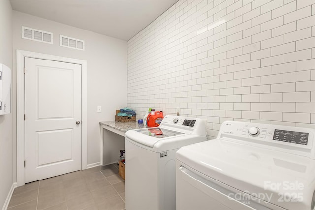 clothes washing area featuring light tile patterned floors, tile walls, and washer and dryer