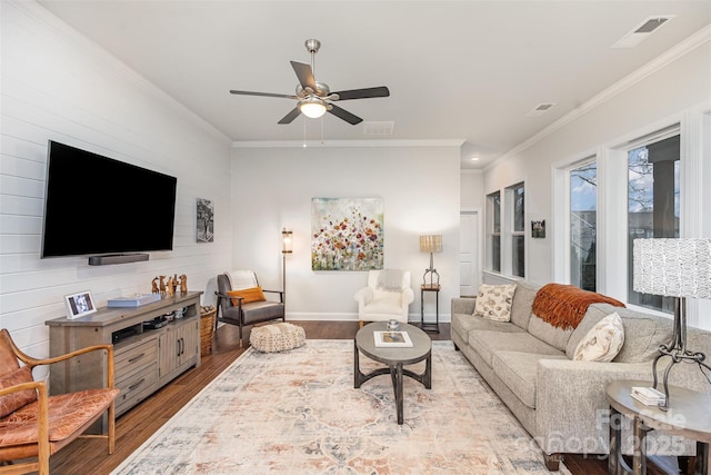 living room with ceiling fan, wood walls, crown molding, and light hardwood / wood-style floors